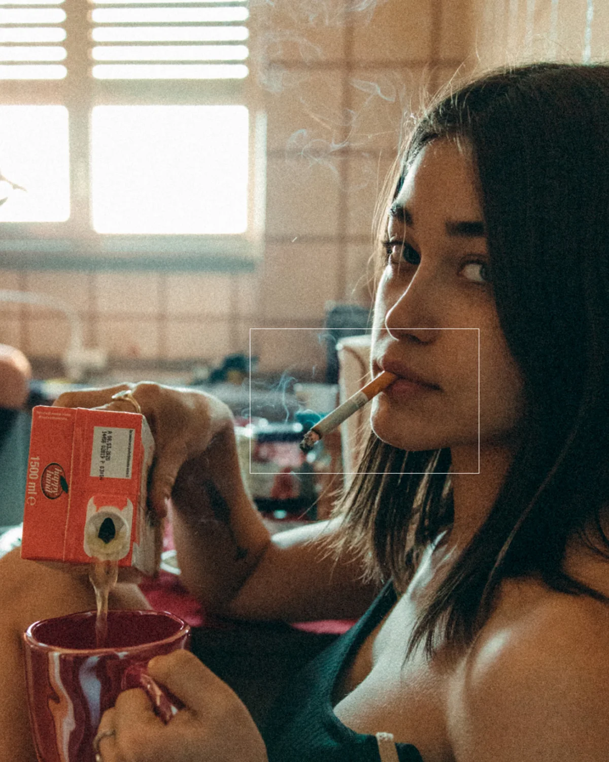 Donna che fuma sigaretta mentre versa succo di frutta in tazza. Stile di vita rilassato con bevanda e fumo.