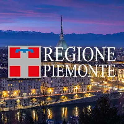 Piemonte, Italia: vista notturna di Torino con la Mole Antonelliana, il fiume Po e le Alpi sullo sfondo. Bandiera del Piemonte in primo piano.